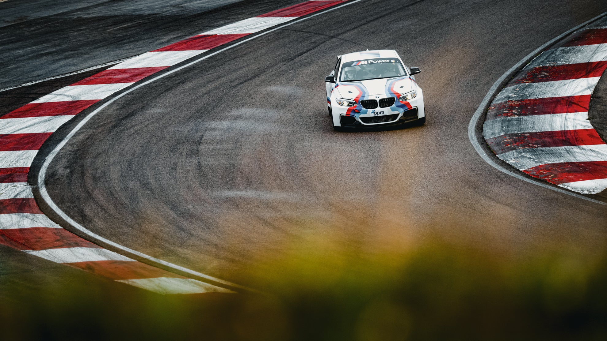 BMW M240i Cup auf der Rennstrecke zwischen zwei Curbs