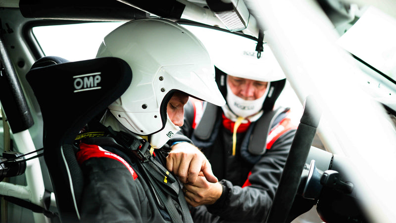 Father and son helping each other with their seatbelts in the car at a trackday