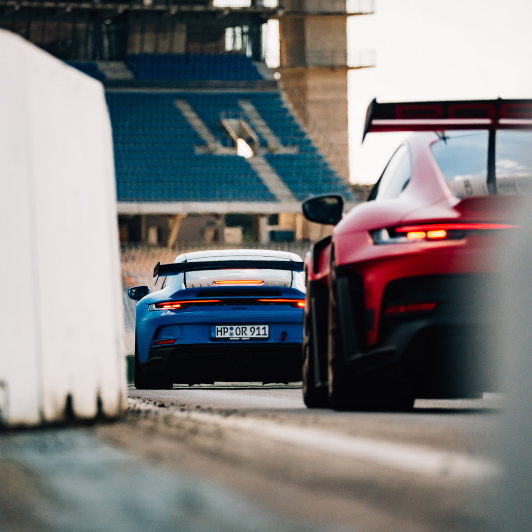 Porsche 992 GT3 in Shark Blue gefolgt von einem roten Porsche 992 GT3 RS auf dem Hockenheimring.