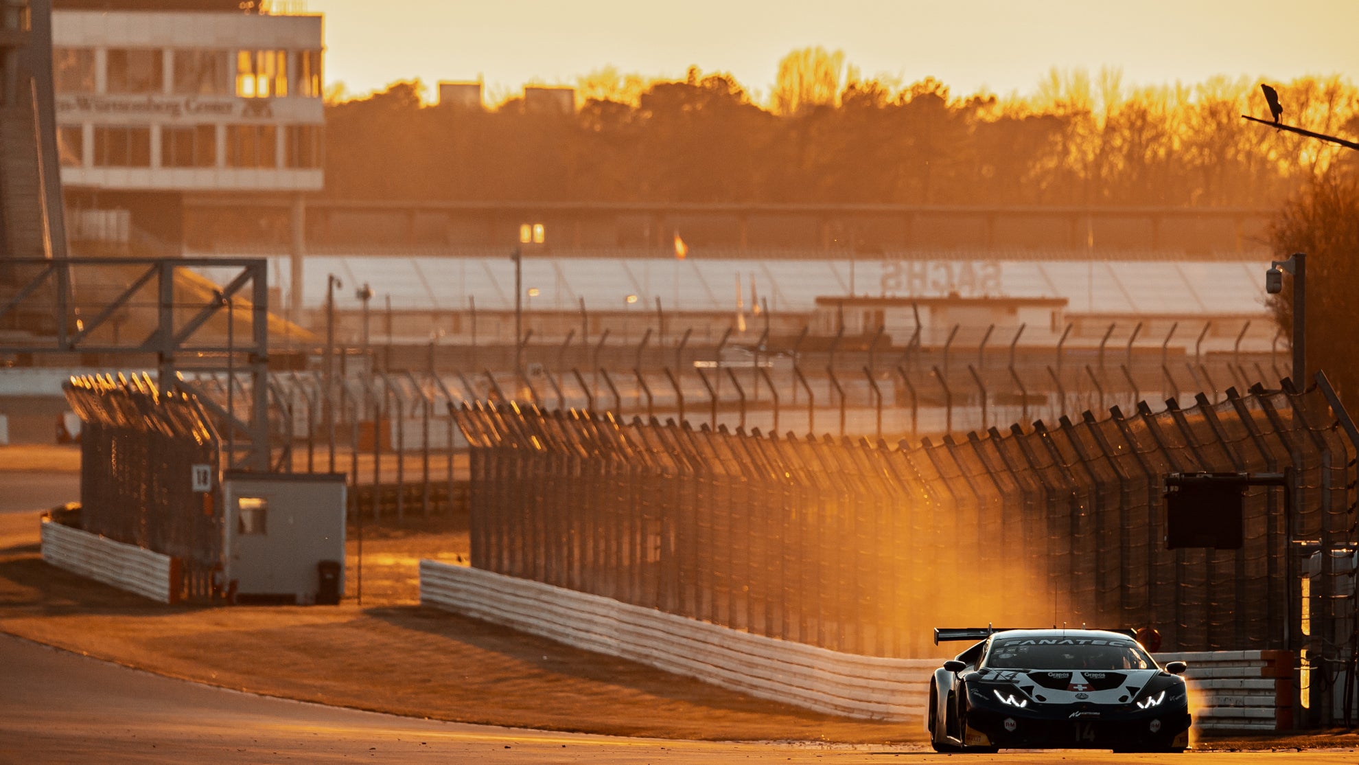 Lamborghini Huracan GT3 EVO beim Sonnenuntergang auf einer Rennstrecke.