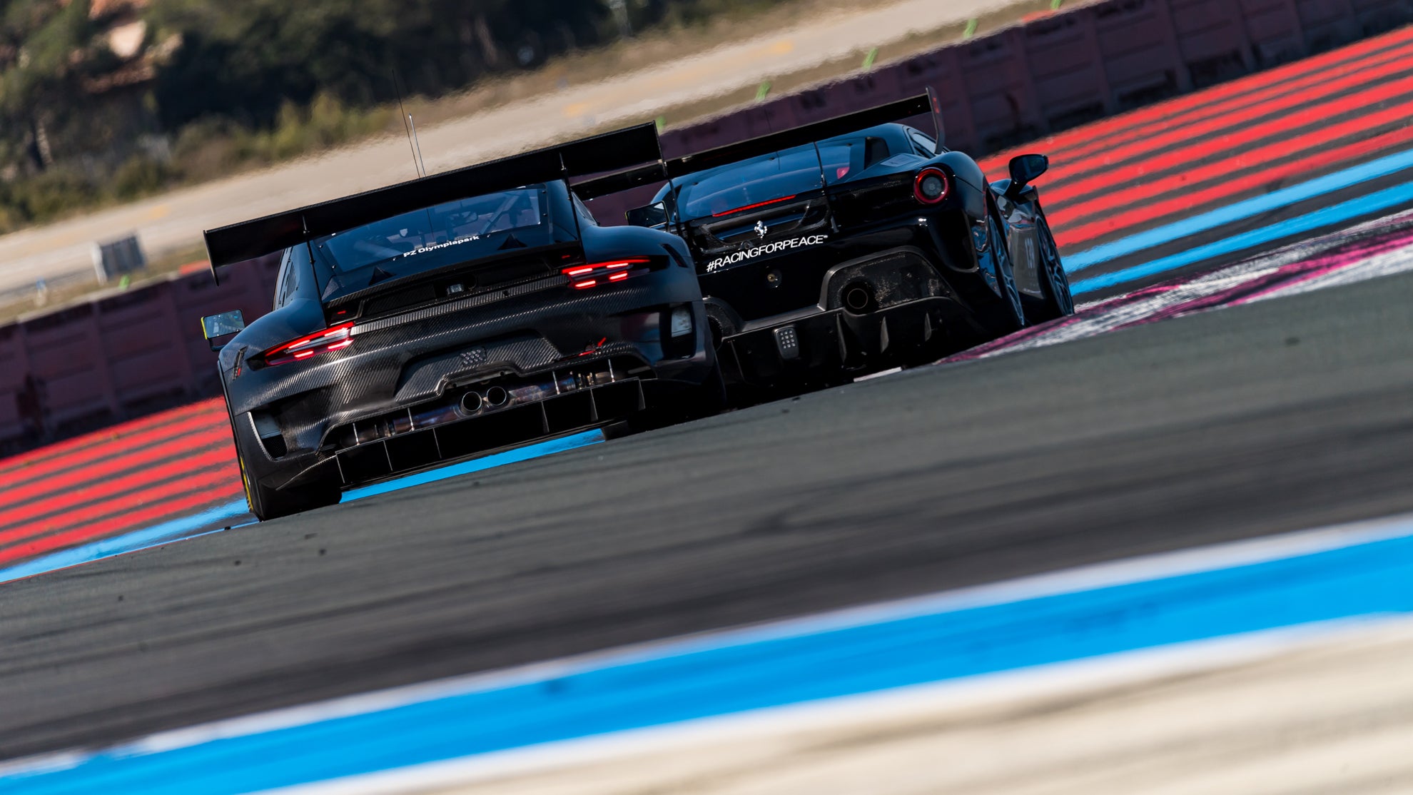 Carbon Porsche 991 GT3R hinter einem schwarzen Ferrari 296 Challenge Evo auf dem Circuit Paul Ricard.