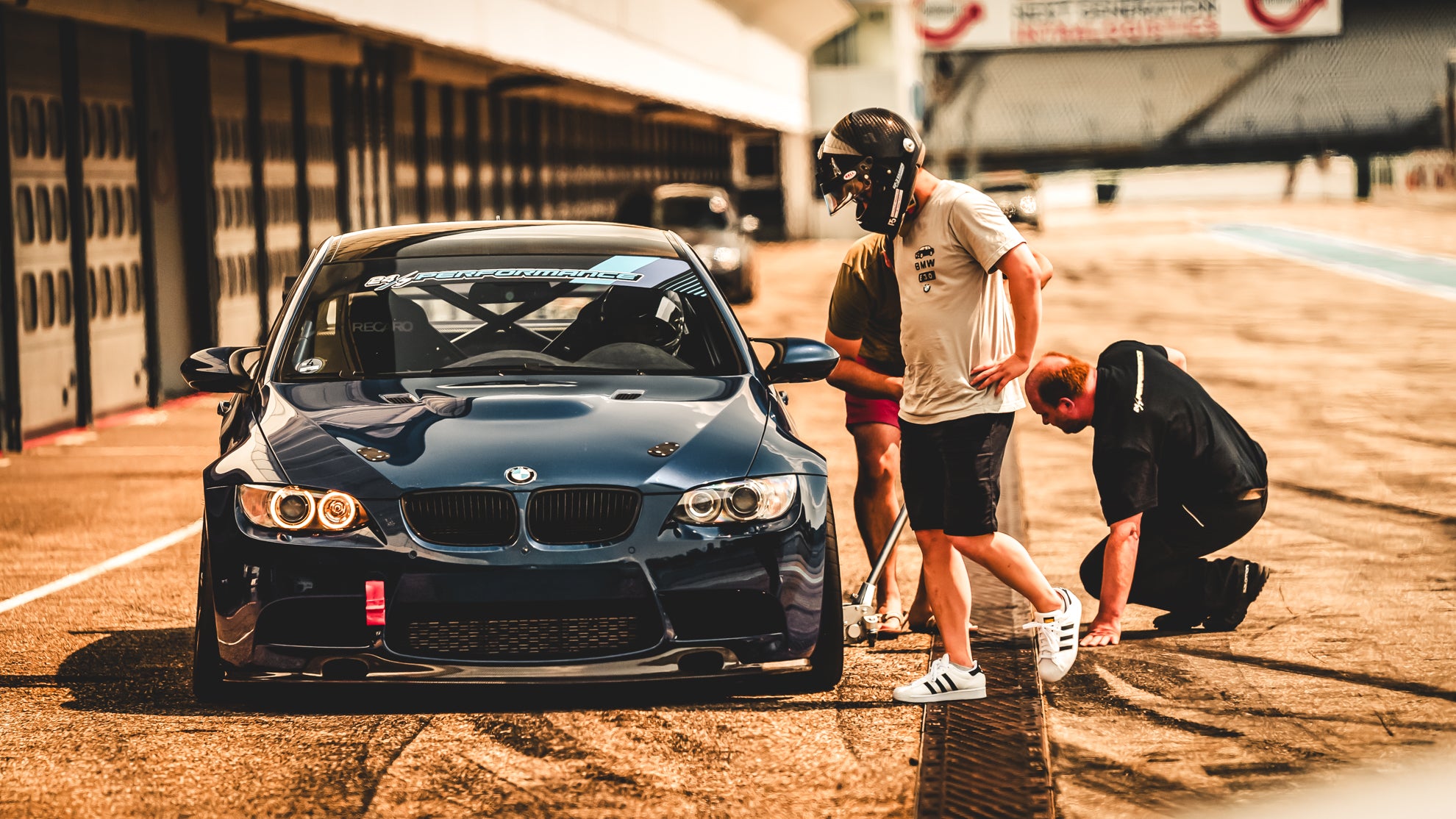 Blauer BMW e92 M3 von 24/7 Performance in der Boxengasse des Hockenheimrings mit einem Fahrer und Machanikern.