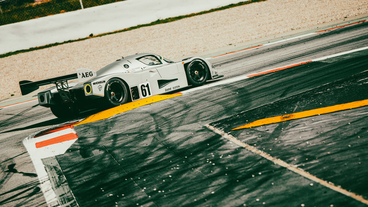Silver Group C prototype with race number 61 at the exit of a corner on a circuit