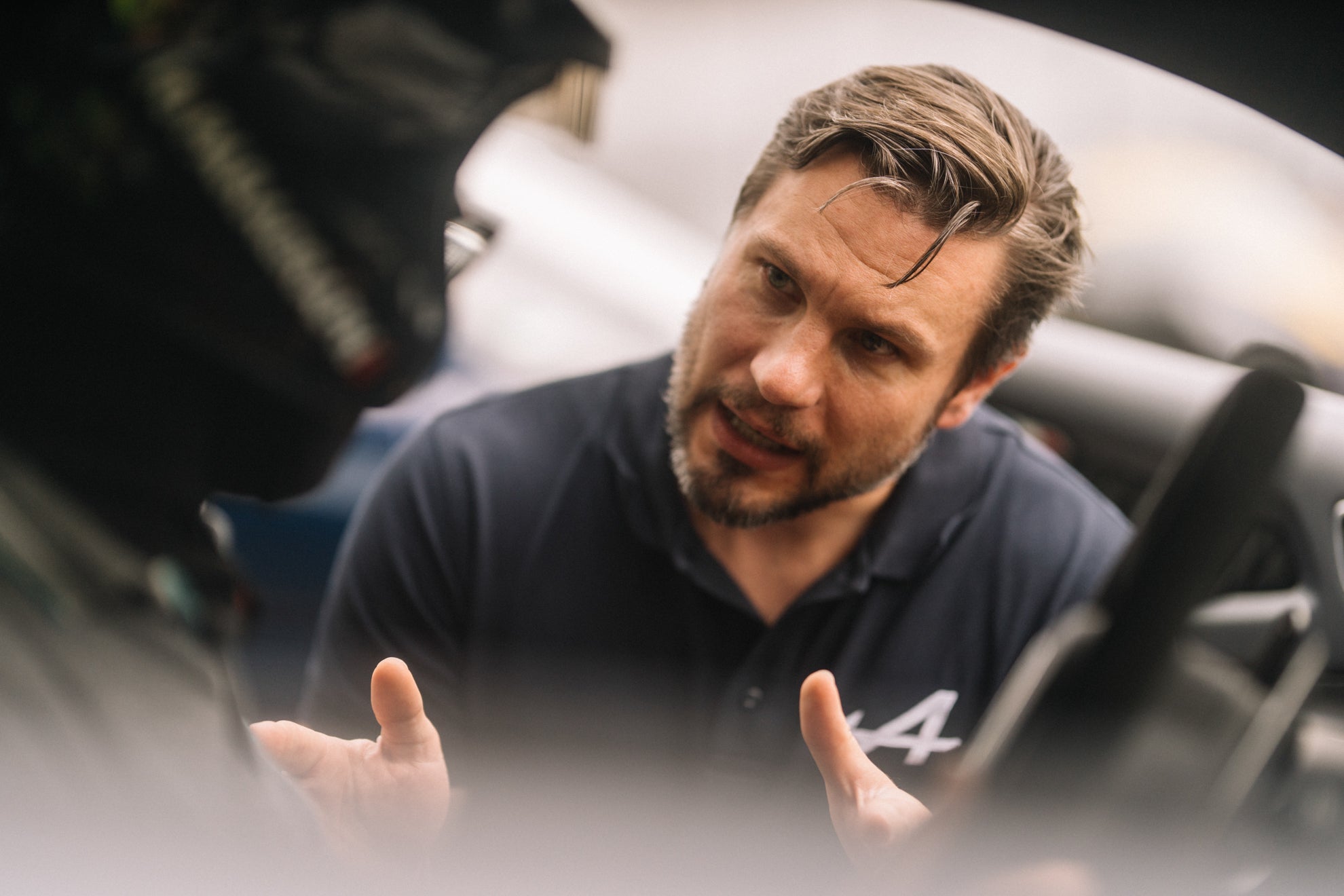 Motorsport Coach bei der Alpine Track Experience, der einem Teilnehmer die Ideallinie erklärt.