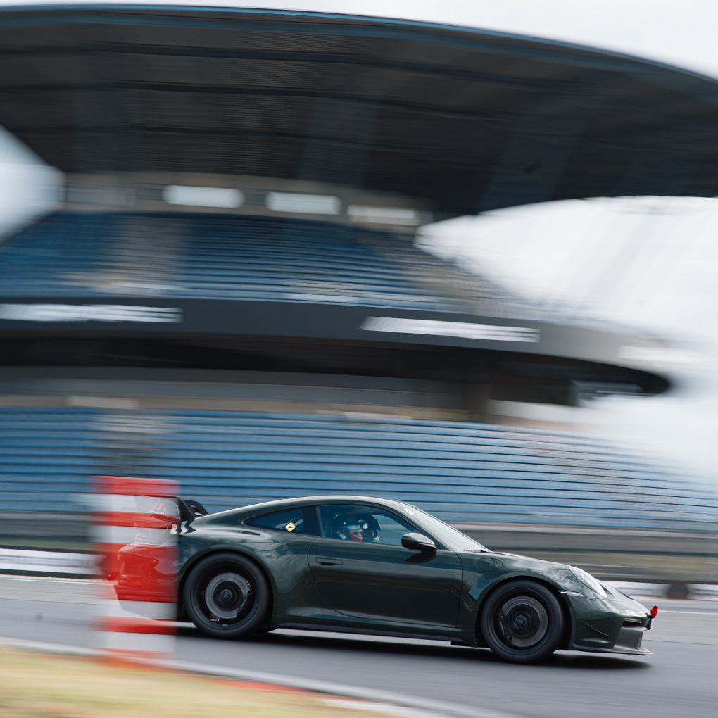 Porsche 992 GT3 in unkelgrün vor der Mercedes-Tribüne auf dem Nürburgring bei einem Afterwork Trackday.