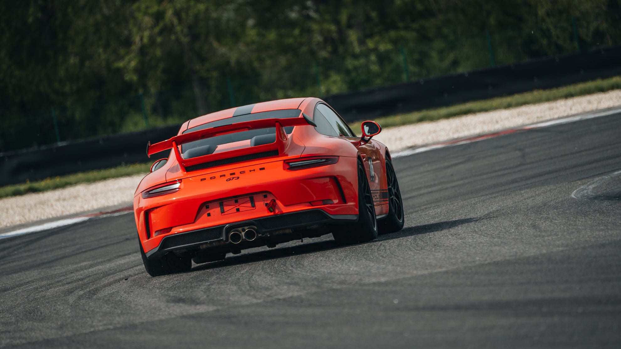 Orangener Porsche 991 GT3  mit schwarzen Felgen in der Heckansicht.
