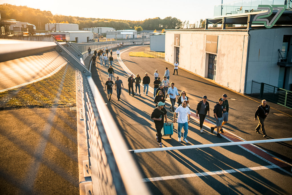 Teilnehmer eines TWENTYSEVEN Trackdays gehen im goldenen Abendlicht über die Rennstrecke am Bilster Berg