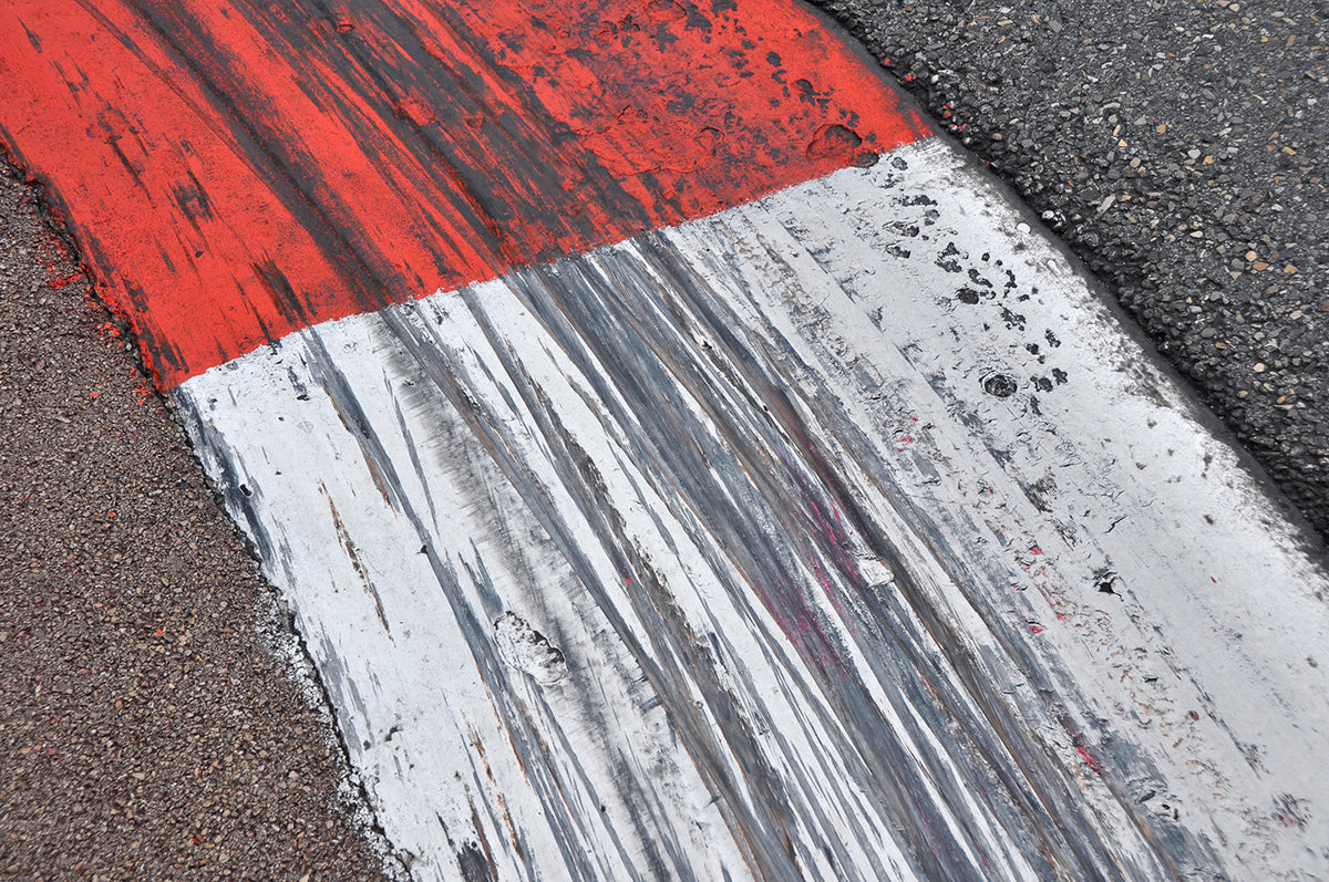 Close-up of a red and white kerb at the edge of a circuit, covered in black tyre marks