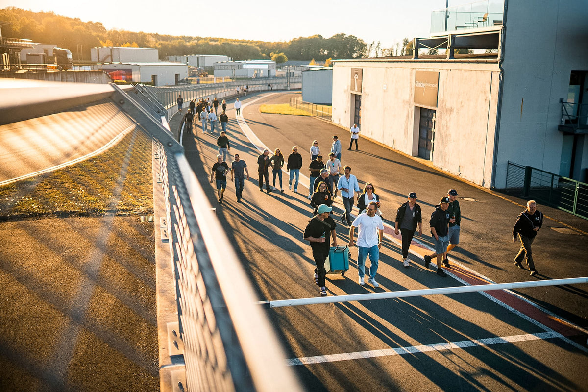 Participants at a TWENTYSEVEN trackday walking the Bilster Berg circuit in the golden evening light