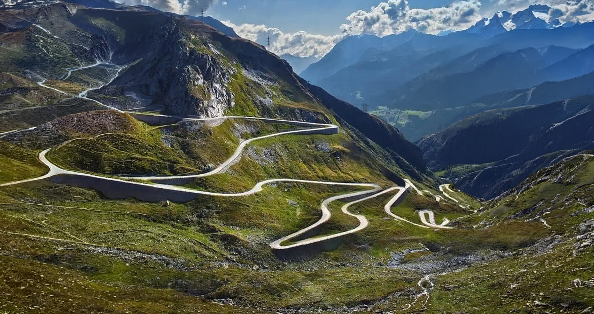 Kurvenreiche Alpenstraße mit Serpentinen in einer Berglandschaft – Symbol für Touren und Events von TWENTYSEVEN Trackdays.